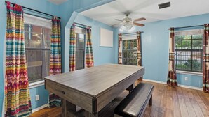 A room with a wooden dining table, benches, and colorful curtains.