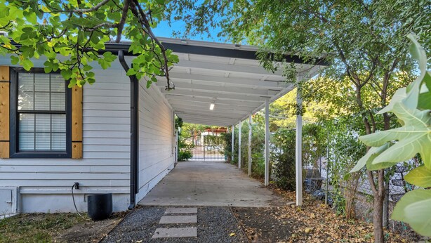 A covered porch with a pathway leading to a gated entrance.