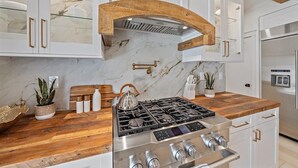 A modern kitchen with white cabinets, a wooden countertop, a stainless steel stove, and a built-in oven. - 🌸Posh Bungalow 🌴near Anna Maria Beaches, IMG and LECOM (Bradenton)