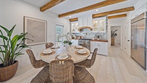A modern kitchen with white cabinets, a stainless steel refrigerator, and wooden beams on the ceiling. - 🌸Posh Bungalow 🌴near Anna Maria Beaches, IMG and LECOM (Bradenton)