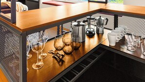 Una encimera de cocina con varios vasos, una cafetera y un hervidor.