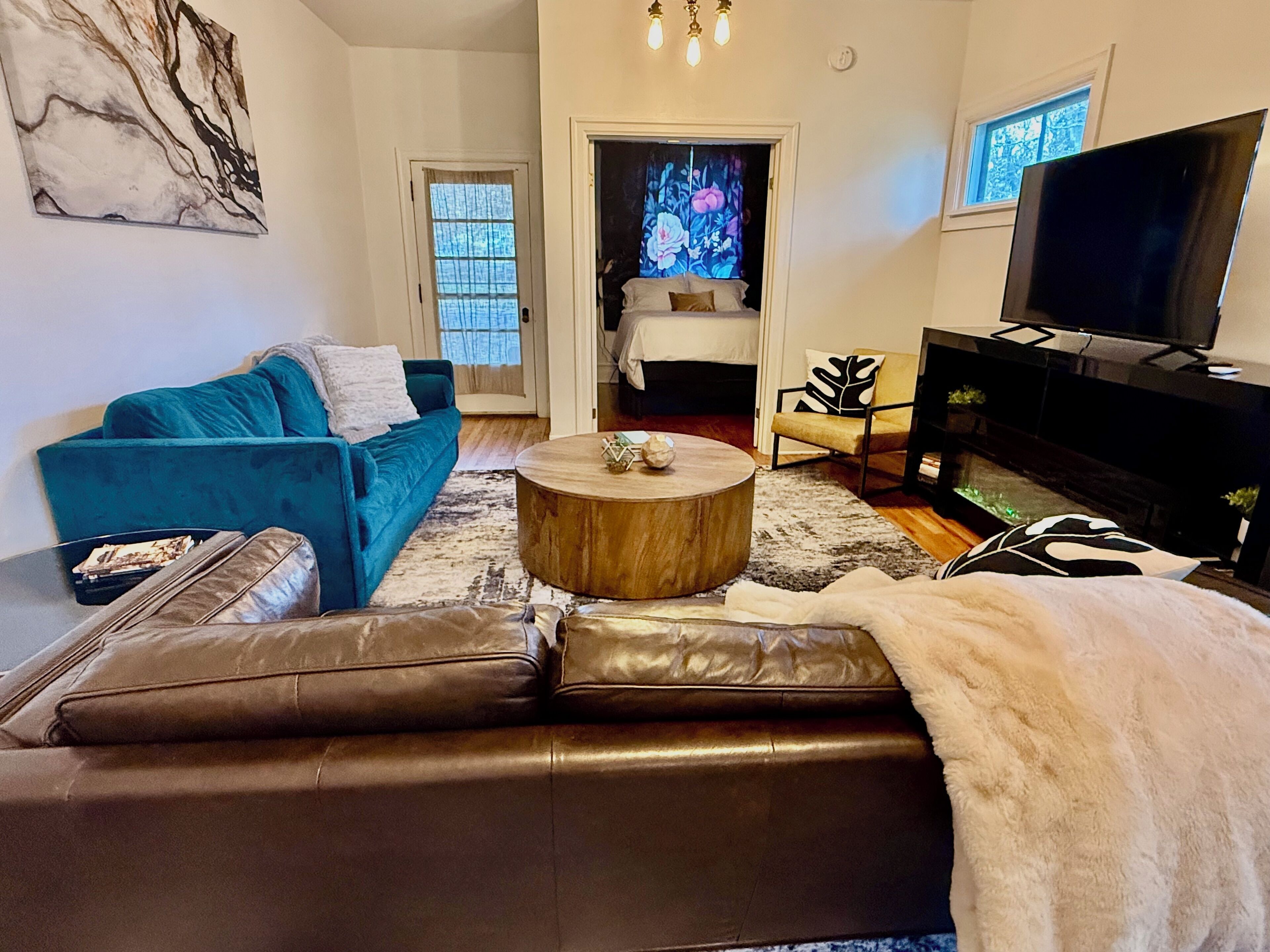 A living room with a blue sofa, a brown leather couch, a wooden coffee table, a TV, and a fireplace.