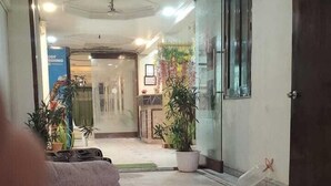 A hallway with a marble floor, potted plants, and a closed door on the right. - Hotel Manglam Inn (Lucknow)
