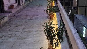 A corridor with potted plants lined up on one side, a tiled floor, and a ceiling with colorful lights. - Hotel Manglam Inn (Lucknow)