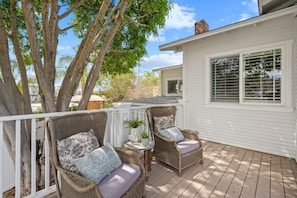 A covered outdoor deck with wicker furniture and a potted plant.