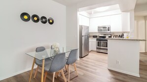 A modern kitchen with a glass dining table, grey chairs, and a central island. - 2-bedroom apt in Marina del Rey with pool, jacuzzi, gym, free parking! (Marina del Rey)