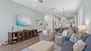 Uma sala de estar ampla, com um conjunto de sofás, um armário de madeira e uma área de jantar.
