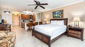 Una habitación de hotel con cama, escritorio, silla, zona de comedor y cocina.