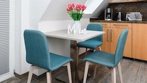 A dining area with teal chairs, a white table, and a vase of pink tulips. - Helle Ferienwohnung fur Zwei Personen in Bensersiel (Esens)