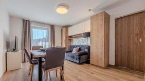 Une pièce moderne et bien éclairée, comprenant une table à manger, des chaises, un canapé et un téléviseur.