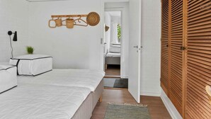 Camera da letto con un letto, un comodino con una lampada, un cesto appeso e un armadio con ante a persiana.