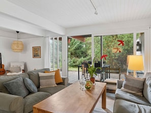 Een moderne woonkamer met een bank, salontafel en een eethoek.