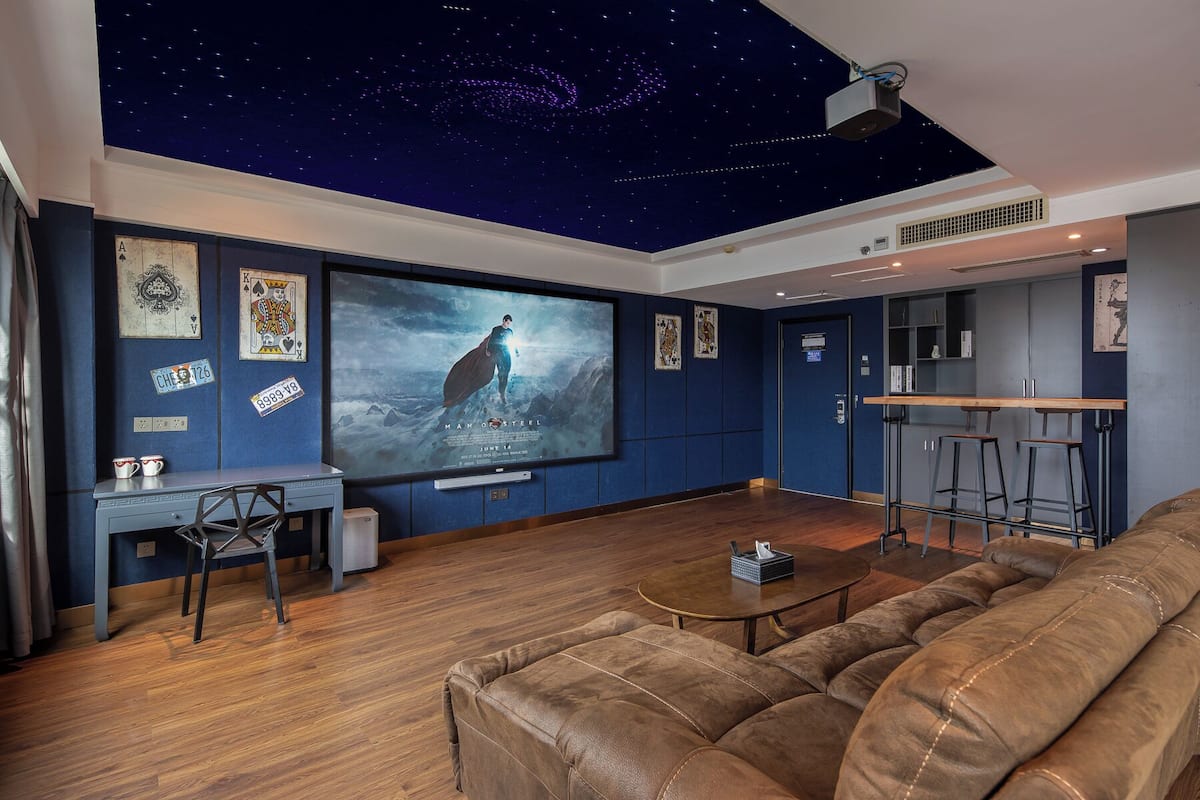 Un salon moderne avec un plafond étoilé, un grand téléviseur à écran plat, une table basse en bois et un canapé en cuir.