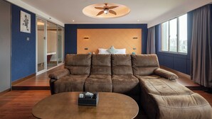 A modern living room with a sectional sofa, a round coffee table, and a ceiling fan. - LiangZhi Huipin Hotel (Haikou)