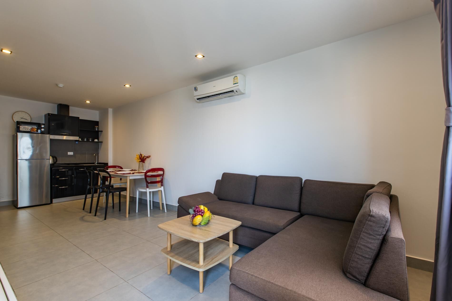 A modern living room with a sofa, a small coffee table, and a dining area with chairs and a table.