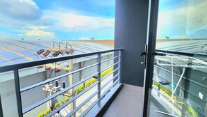 Uma varanda com vista para painéis solares e um edifício com fachada de vidro.