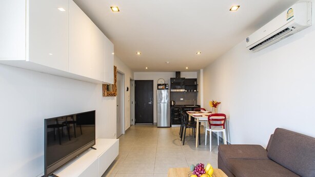 Uma sala de estar moderna com televisão de tela plana, um sofá marrom e uma mesa de centro de madeira com frutas.