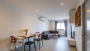 Uma sala de estar moderna com área de jantar, sofá, TV e um painel decorativo na parede.