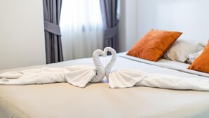 Cama bem arrumada com toalhas brancas dispostas em formato de coração.