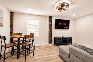 Una sala moderna con comedor, un televisor de pantalla plana en la pared y una mesa de comedor de madera con sillas.