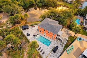 Uma casa com piscina, cercada por árvores e um pequeno lago.
