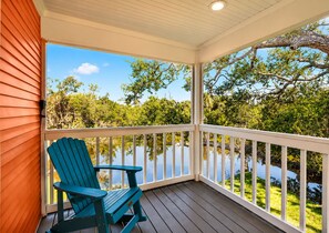A covered porch with a view of a body of water and trees.