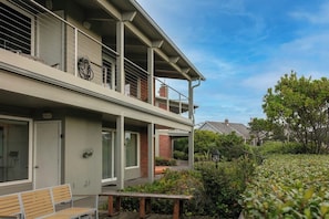 A two-story building with a balcony, a bench, and a garden area.