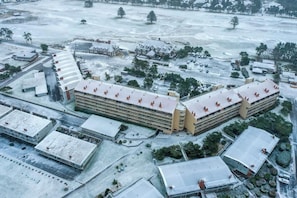 An aerial view of a large building complex with multiple structures, including a central building with a curved roof and several smaller buildings with flat roofs.