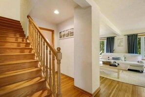 A wooden staircase leading to a living area with a white sofa and a coffee table. - Waterfront Home|Dock & Kayaks|5 Min to Baileys Harbor (Baileys Harbor)