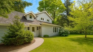 Une maison à deux étages dotée d’un porche abrité, d’une pelouse bien entretenue et d’arbres adultes.