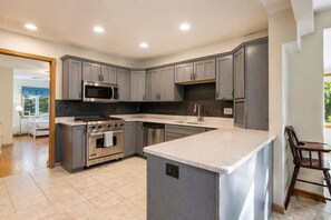 A modern kitchen with grey cabinets, stainless steel appliances, and a large island. - Waterfront Home|Dock & Kayaks|5 Min to Baileys Harbor (Baileys Harbor)
