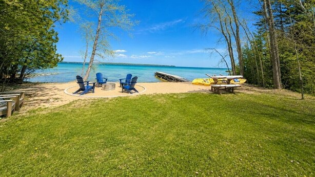 Un cadre idyllique au bord de la plage, avec des chaises, une table de pique-nique et un kayak.