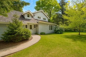 A two-story house with a covered porch, a well-maintained lawn, and mature trees.