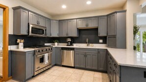 A modern kitchen with grey cabinets, stainless steel appliances, and a large island.