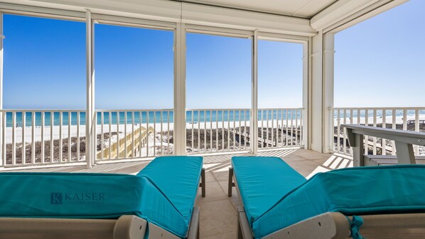Ein Balkon mit zwei Loungestühlen, freier Blick auf den Strand und ein Holzboden.