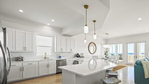 A modern kitchen with white cabinetry, a central island, and pendant lighting.