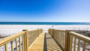 A wooden boardwalk leading to a beach with clear skies.