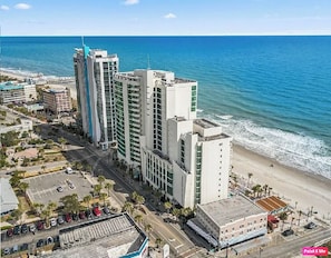 A high-rise hotel with multiple floors, a parking lot, and a beach view. - Oceanfront Paradise with Private Balcony! (Myrtle Beach)