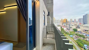 Un balcone con vista sulla città, una porta scorrevole e un piccolo angolo relax.