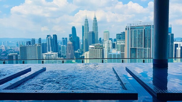 Una piscina sul tetto con vista sulla città, inclusi i Petronas Towers.