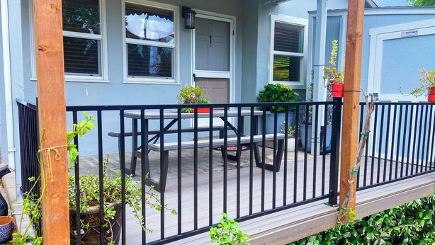A covered porch with a table and chairs, surrounded by a black metal railing. - Sweet Home with Ample Parking. Only 1-min to Freeway! (Sacramento)