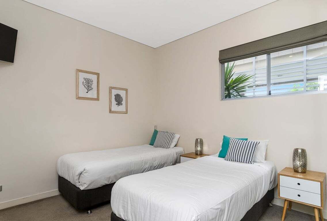 A bedroom with two beds, a window with a view, and two framed pictures on the wall.