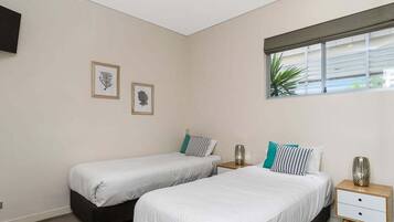 A bedroom with two beds, a window with a view, and two framed pictures on the wall.