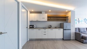 A modern kitchen with white cabinets, a built-in microwave, a kettle, and a refrigerator. - Ocean View Apt - 1BR T2-613 (Chalong)