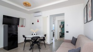 A modern kitchen with a black refrigerator, a dining table with chairs, and a hanging light fixture. - Maison Regina Giovanna (Sorrento)