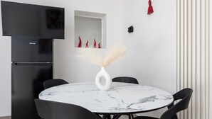 A modern kitchen with a black refrigerator, a flat-screen TV, and a marble-top dining table with black chairs. - Maison Regina Giovanna (Sorrento)