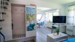 Ein modernes Wohnzimmer mit Treppe, Essbereich und Fernseher.
