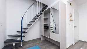 Ein modernes Interieur mit Treppe, eingebauten Regalen und einer blauen Bank.