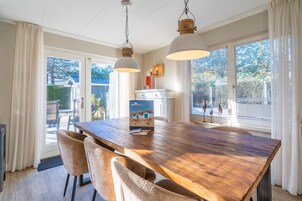Un comedor con mesa de madera, sillas color beige y lámparas colgantes.