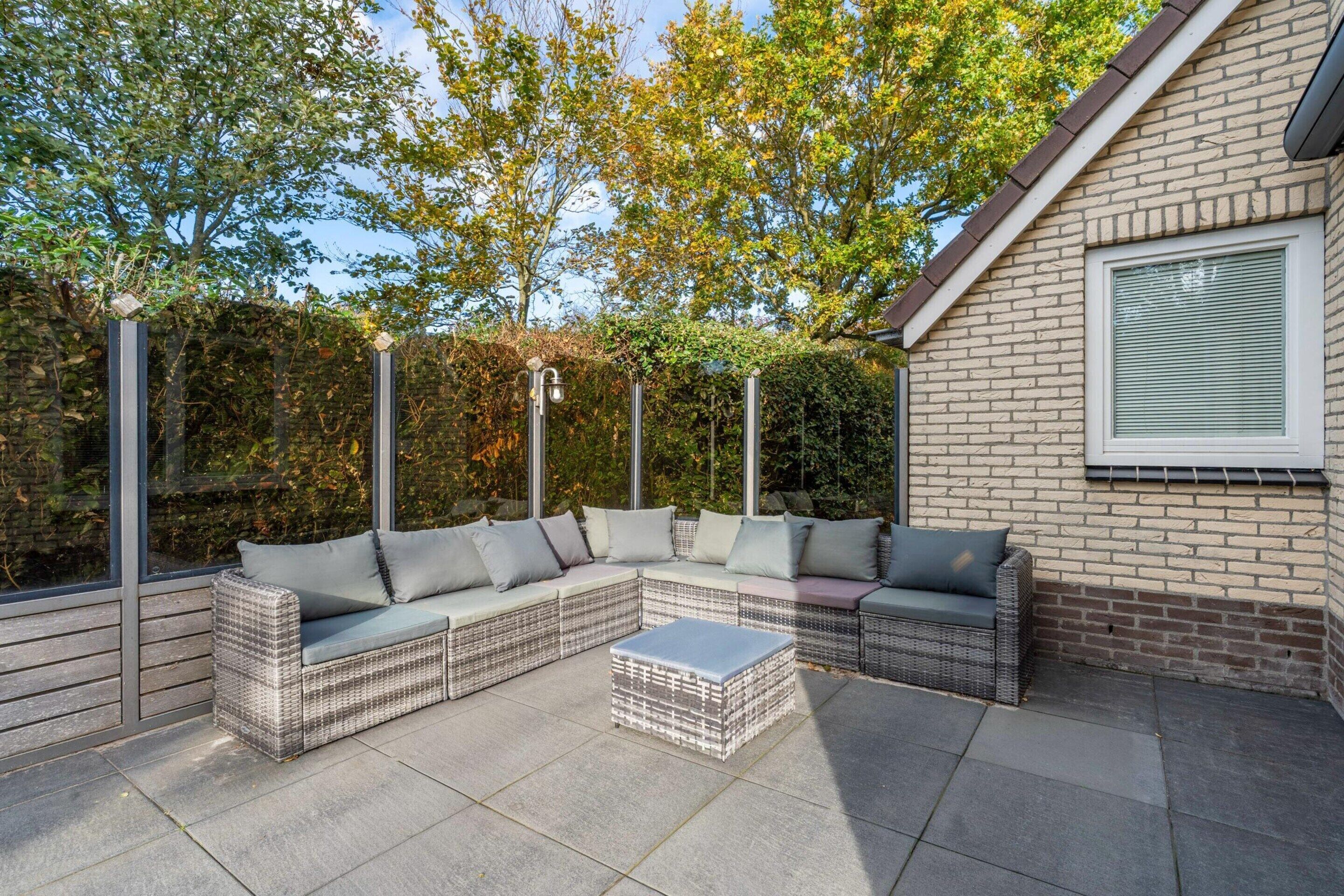 A modern outdoor patio with a sectional sofa, a coffee table, and a brick wall.